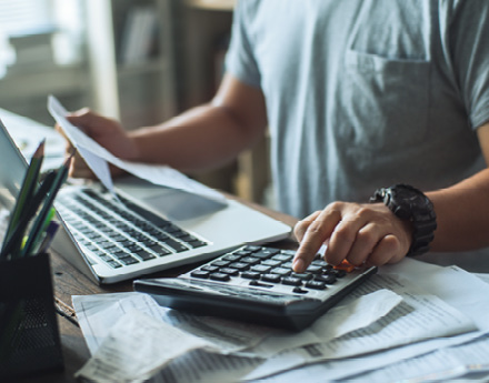 A person working with a laptop and a calculator