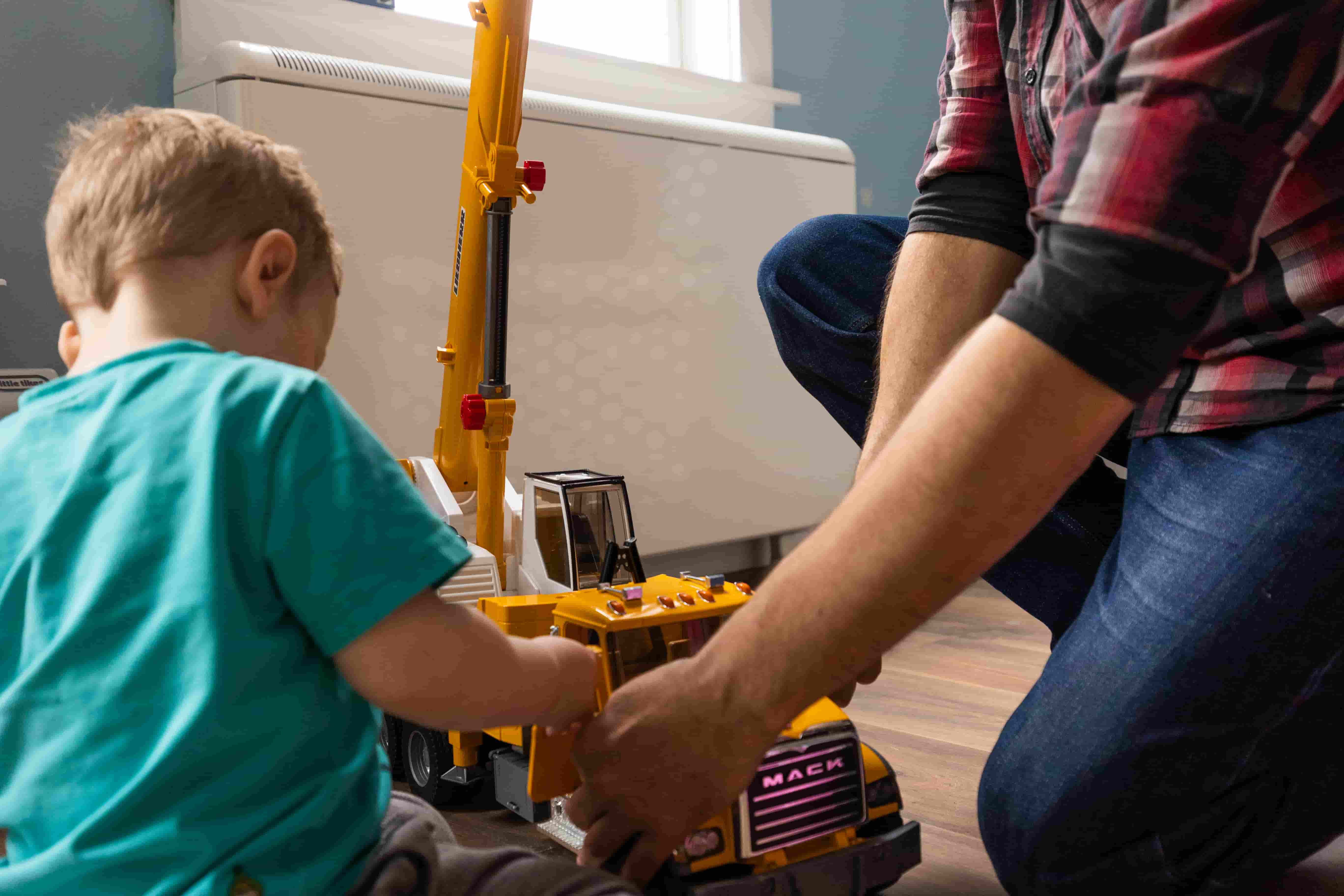 A parent and a child playing with a construction crane toy
