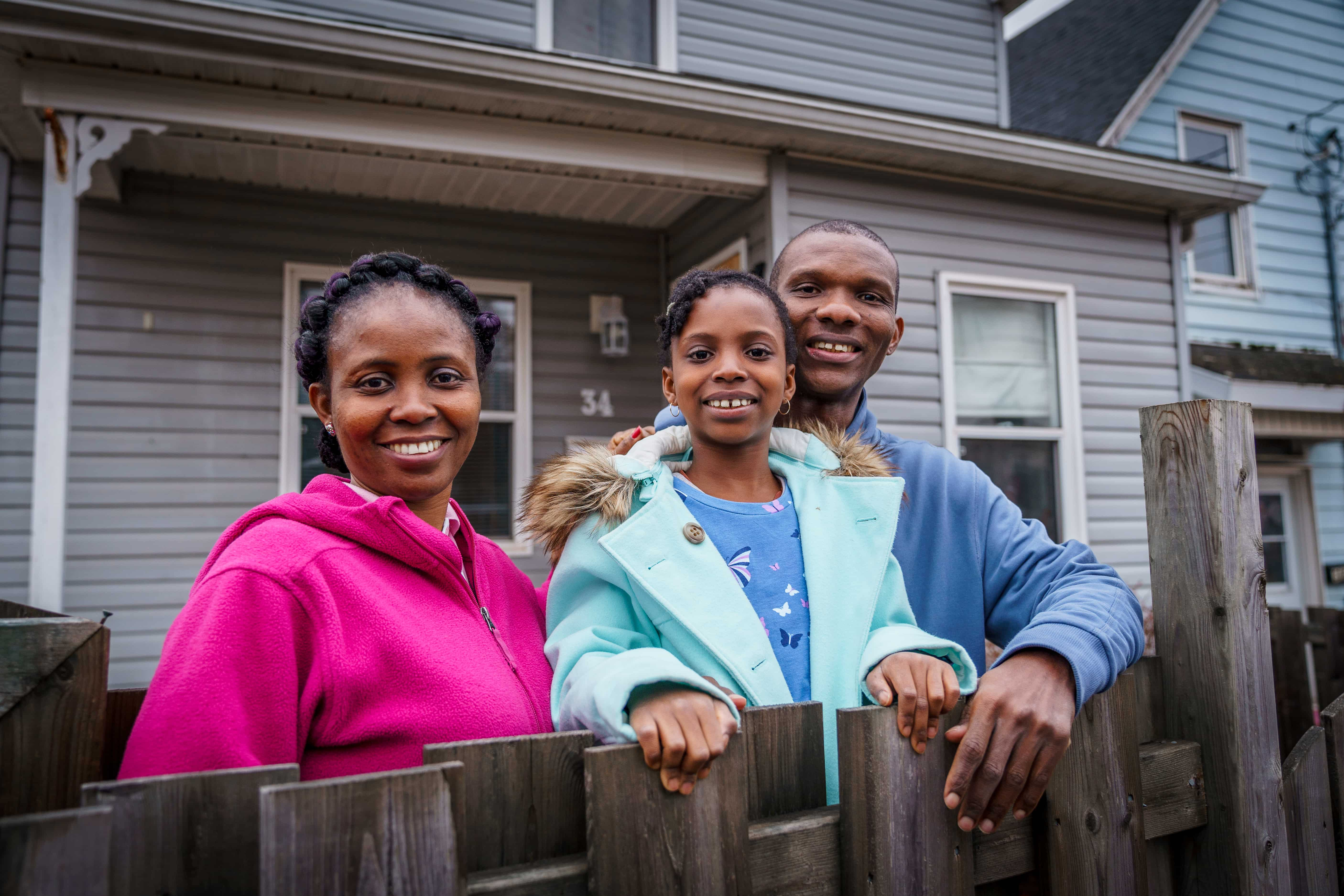 Family of three standing in front of a house